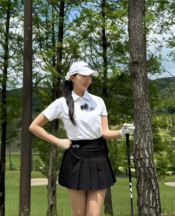 흰 피케 셔츠와 검은 플리츠 스커트 차림으로 드라이버를 짚은 강소율 프로